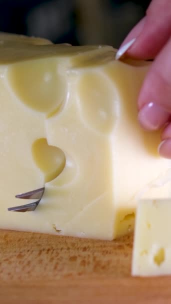 女性の手は木製の切断板にナイフでチーズを切ります 高品質の4K映像 垂直ビデオ — ストック動画