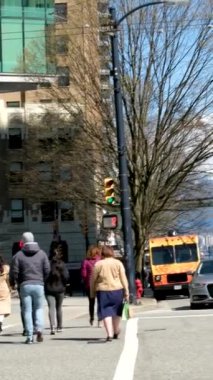 Burrard İstasyonu 'ndaki ofis binaları çalışanları tramvay trafik ışıklarına doğru koşuşturuyor. Erkekler ve kadınlar caddeyi geçerek toplu taşıma şehrine giderler. Kanada Vancouver 12.04.2023