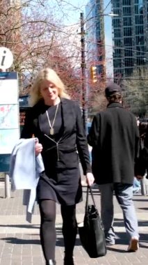 Burrard İstasyonu 'ndaki ofis binaları çalışanları tramvay trafik ışıklarına doğru koşuşturuyor. Erkekler ve kadınlar caddeyi geçerek toplu taşıma şehrine giderler. Kanada Vancouver 12.04.2023