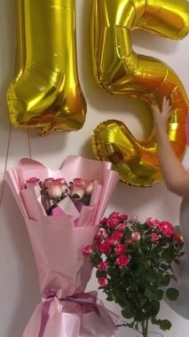 Genç kız 15. doğum gününü kutluyor balonlar beyaz duvarda çiçek numaraları sosyal ağlar için video çekimleri internet tatil dekorasyonları oda dekorasyonları. kot pantolon
