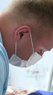 En son teknoloji temizliği ve diş beyazlatma hemşiresi ve doktor genç bir dişçinin dişlerini tedavi ediyor. Genç bir kızın maskeleri eldivenleri temizleme temizliği yapıyor. Klinikteki en son cihaz.