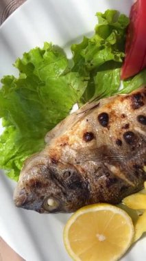 Kızarmış dorado balığı ve patates kızartması, baharat ve limon, arka planda patates, gözleme ve salata. Restoran kahvaltısı.