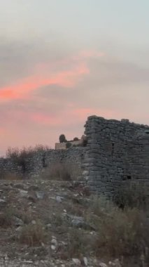 Arnavutluk 'un Saranto kentindeki yol. Gün batımında dağlarda dallanmış yollar geleneksel danslarla şato restoranına gidiyor. Yiyecek, bulutlar yüzünden gökyüzünde kızıl güneş ışınları bırakıyor.