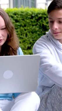 Oğlan, elinde dizüstü bilgisayarla gülen kız videolar seyrediyor. İlginç videolar çekiyor. Ders yapıyor, sorunları çözüyor. 