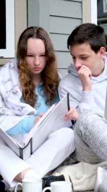 okul çağındaki çocuklar evlerinin kapısında ev ödevlerini yapan çocuklar dizüstü bilgisayarcı kızın ellerinde büyük beyaz bir klasörü var iki bardak utanç verici ilk ilişki arkadaşlığı 