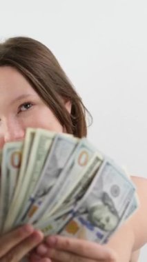 Beyaz önlüklü genç bir kız 100 dolarlık banknotlar gösteriyor. İyi bir çocukluk dönemi. Pahalı bir şekilde ödenmiş bir model. Saçlarını düzleştirir.