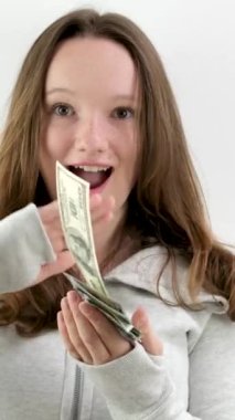 Mutlu genç kız farklı yönlere 100 dolarlık banknotlar saçıyor yavaş çekim videosu beyaz arka plan spor ceketli zengin bir adamın parayı çöpe atması üzerine. Geleceği düşünmüyorum.