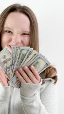 Genç kız, büyük miktarda para gösteriyor. Ailesinden para çalan bir tomar para gösteriyor. Stüdyoda beyaz arka planda 100 dolar. Faturalar ve genç bir kadın.