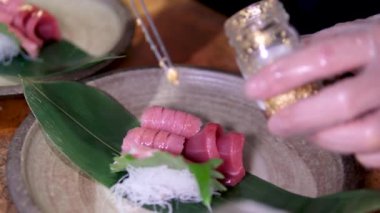 Yenebilir altın süslemelerle süslenmiş sosla kaplanmış pirinç vermicelli ile ton balığı eti, restoranda yemek pişiren bir erkeğin eldiveni için nefis bir hazırlık bırakır. Sushiya.