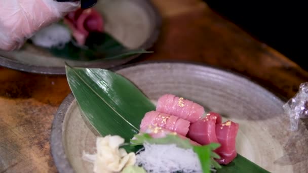 金枪鱼鱼肉配米粉 铺上酱汁 上面撒满了黄金装饰 可食用的莴苣叶 用一只戴着手套的雄性手在餐馆里烹调 很好吃 Sushiya — 图库视频影像
