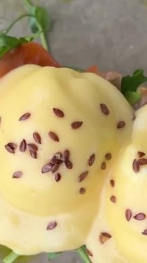 Hafif tuzlu somonlu çörekler üzerine Bendict yumurtaları ve güzel peynirli krema. Restoranda servis edilen lezzetli kahvaltı tabağında keten tohumu serpiştirilmiş otlar. yaz sabahı