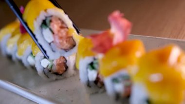 Yakın plan, beyaz kil tabakta mango suşisi. Beyaz arka planda izole edilmiş mango ve krem peynirli suşi aromalı yüksek kalite 4K görüntü.