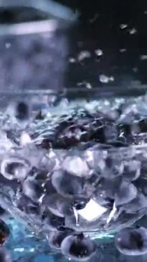 Bir kadın, küçük plastik bir kutuda, musluğun altında yaban mersinlerini yıkıyor. Yüksek kalite 4k görüntü