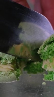 Bıçakla yeşil badem kurabiyesi kes. kireç fıstıklı zeytin yeşil makarna cam bir masada çelik bıçakla kesilmiş.
