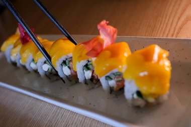 Yakın plan, beyaz kil tabakta mango suşisi. Beyaz arka planda izole edilmiş mango ve krem peynirli suşi aromalı yüksek kalite 4K görüntü.