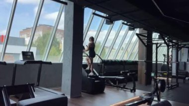 Genç bir kadından güzel bir figür yarat spor salonunda çalışan genç bir kız egzersiz makinesinde bacakları pompalayan kulaklıklar takan Avrupalı Ukrayna Vinnitsa 09.09.2023