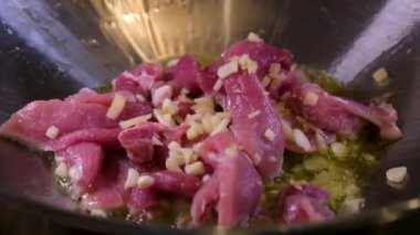 Kızartma tavasında sığır eti pişirmek için doğranmış sarımsak ve zencefil ekleyin. Zeytinyağında pişmiş çiğ et yakın plan Oriental gıda vermicelli Wok sıcak yağ sıçramalarını pişirmeye başlar. Pişerken çiğ et