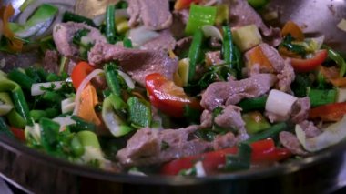 Kızartma tavasında sığır eti pişirmek için doğranmış sarımsak ve zencefil ekleyin. Zeytinyağında pişmiş çiğ et yakın plan Oriental gıda vermicelli Wok sıcak yağ sıçramalarını pişirmeye başlar. Pişerken çiğ et