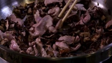Kızartma tavasında sığır eti pişirmek için doğranmış sarımsak ve zencefil ekleyin. Zeytinyağında pişmiş çiğ et yakın plan Oriental gıda vermicelli Wok sıcak yağ sıçramalarını pişirmeye başlar. Pişerken çiğ et