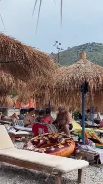 Güzel bir yaz günü, sabahın erken saatlerinde Arnavutluk Riviera 'sı boyunca resim gibi yazlık kulübeler. Arnavutluk 'un Borsh köyündeki sahil 08.08.2023