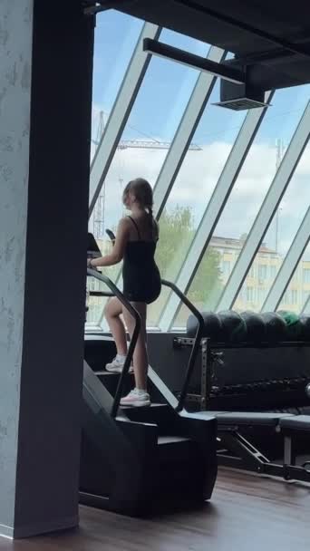若い年齢の若い女性10代の少女から美しい図を作成する 運動機械で脚をポンプで働く ステップを歩く ヘッドホン ヨーロッパのウクライナVinnitsa 2023 — ストック動画