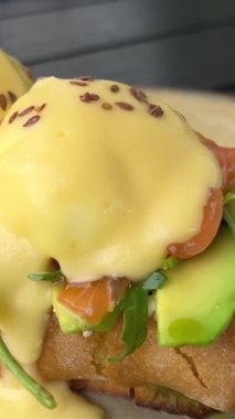 Hafif tuzlu somonlu çörekler üzerine Bendict yumurtaları ve güzel peynirli krema. Restoranda servis edilen lezzetli kahvaltı tabağında keten tohumu serpiştirilmiş otlar. yaz sabahı