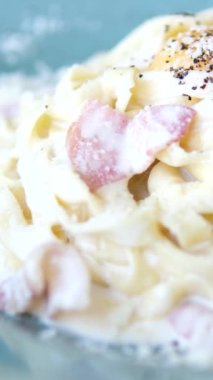 Makarnayı bir tabaktan carbonara sosuyla alan çatala yakın çekim. Çatallı sıcak spagetti. İtalyan mutfağı ve ev yemeği konsepti. Yüksek kalite 4k görüntü