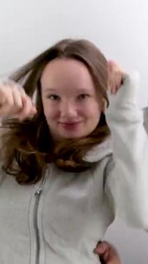 Kulaklıklı neşeli bir aile beyaz eşofmanların arka planında baş parmak göstererek dans ediyor eğlenceli aile sporları yapıyor mutlu aile anne kız baba. Neşeli müzik