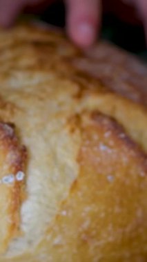 Tam tahıllı ekmek mutfak ahşap tabağına konmuş ve şefin elinde altın bıçak var. Masanın üzerinde taze ekmek var. Mutfak masasında taze ekmek sağlıklı beslenme ve geleneksel fırın konsepti