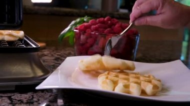 Elektrikli waffle demiriyle lezzetli waffle hazırlama süreci yumurtanın malzemelerini yeniliyor. Un, şekere yakın yemek tarifi ekliyor. Ahududulu kahvaltı bir dizi video dekore eder.