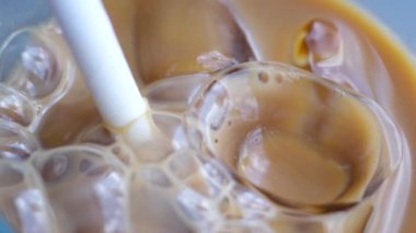 Sütsüz süt yulaflı buzlu latte ya da lezzetli bir tatlı içeceğin içinde muz bademli hindistan cevizi sütü yakın plan makro fotoğrafçılığa buz ekle. çeşitli videolar