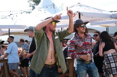 Vancouver 'da izinli insanlar içki alırlar salıncaklara binerler kovboy şapkaları giyerler parkta yürürler Surrey Kanada şehrinde gerçek insanlar 05.20.2023