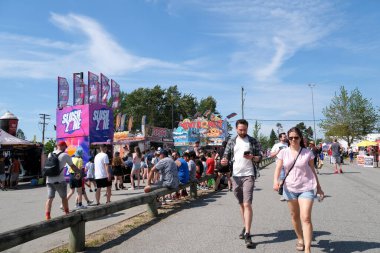 Vancouver 'da izinli insanlar içki alırlar salıncaklara binerler kovboy şapkaları giyerler parkta yürürler Surrey Kanada şehrinde gerçek insanlar 05.20.2023
