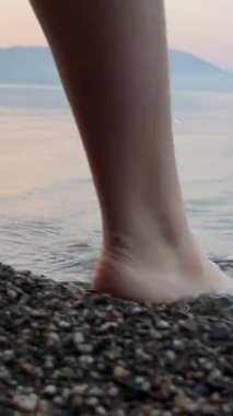 Makedonya ve Arnavutluk sınırında Torino Gölü 'ne giren genç bir kız, şafak vakti çakıl taşlarının üzerine battaniyeye sarılmış tanınmamış insanlar, sadece bacaklar ve berrak su