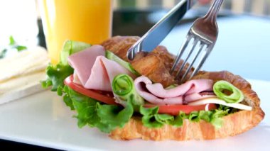 Balyk ve salatalık salatalıklı kruvasan balkondaki sandviçin içinde beyaz tabak pastırma katmanları üzerinde peynir ve portakal suyuyla domatesli lezzetli bir kahvaltı bırakır. Lezzetli yemek öğle yemeği