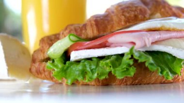 Yumurtalı, etli, domatesli ve Brie peynirli kruvasan Fransa 'da lüks bir otelde sunulan bir tabakta öğle yemeği. Bir gurme için yemeğin tadını çıkar. Portakal suyunun yanında.