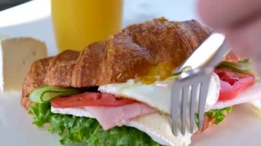 Yumurtalı, etli, domatesli ve Brie peynirli kruvasan Fransa 'da lüks bir otelde sunulan bir tabakta öğle yemeği. Bir gurme için yemeğin tadını çıkar. Portakal suyunun yanında.