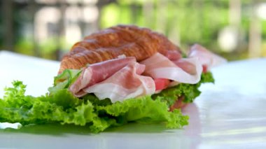 Jamonlu jambonlu kruvasan sandviçi ve domatesli marul sebzeler, Fransa 'da kahvaltıda sağlıklı, pahalı ve zengin peynirleri beyaz tabakta bırakır. pahalı restoran