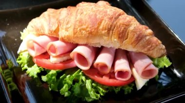 Sandviç ekmeğine sarılmış altı parça domuz pastırması, Brie peynirli kahvaltıyı açık havada domates servis eden siyah tabakta şık bir yemeğe bırakır. yaz