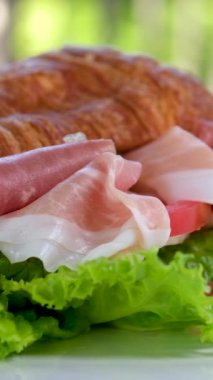 Jamonlu jambonlu kruvasan sandviçi ve domatesli marul sebzeler, Fransa 'da kahvaltıda sağlıklı, pahalı ve zengin peynirleri beyaz tabakta bırakır. pahalı restoran