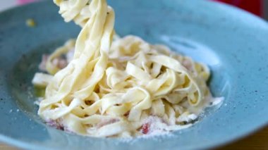 Arka planda Carbonara soslu Linguini makarna. Pastırma, parmesan, yumurta, krema ve biberden yapılmış Carbonara sosu. İtalyan yemeği..