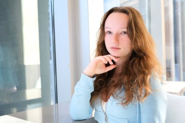 Doğal dudaklı, çıplak makyajlı, temiz tenli ve çenesine yakın eli olan güzel bir kız yüzü. Cilt sağlığı konsepti. Kız eli çeneye yakın.