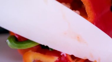 Profesyonel aşçı eldiven giyer, kırmızı dolmalık biber keser. Kahverengi ahşap tahtaya su damlatır. Restoranda çok yakın plan çekilir. Yüksek kalite 4k görüntü
