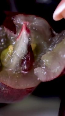 Yağmurdan sonra mavi üzümlü böğürtlen yakın çekim, makro çekim. Fransız manikürlü kadın elleri büyük üzümlerin meyvelerini kırıyor.