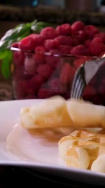 Elektrikli waffle ızgara ızgarasında tatlı waffle hazırlarken çekilen dikey video işlemi yumurta malzemesi şekeri yakın çekim yemek tarifi ekler. Kahvaltıda ahududu yemek ve video dekorasyonu.