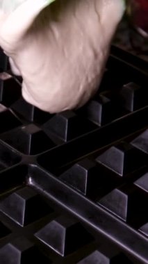 Elektrikli waffle ızgara ızgarasında tatlı waffle hazırlarken çekilen dikey video işlemi yumurta malzemesi şekeri yakın çekim yemek tarifi ekler. Kahvaltıda ahududu yemek ve video dekorasyonu.