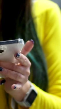 Sarı bir elbisenin arka planına bakan bir kadın telefonda çalışır, mesaj yazar ve sadece akıllı telefon elleriyle sipariş vermek için kadını seçer. Yüksek kalite 4k görüntü