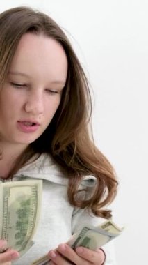 Sakin yüzlü genç bir kadın beyaz arka planda 100 dolarlık banknotlar sayıyor güzel bakımlı saçlar güzellik salonu için para ödüyor. Eski ve yeni banknotlar