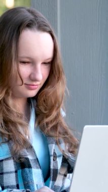 Genç ve mutlu bir kadın laptopunu sokakta bankta otururken kullanıyor. Yüksek kalite 4k görüntü