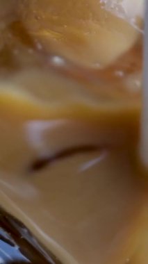 Sütsüz süt yulaflı buzlu latte ya da lezzetli bir tatlı içeceğin içinde muz bademli hindistan cevizi sütü yakın plan makro fotoğrafçılığa buz ekle. çeşitli videolar